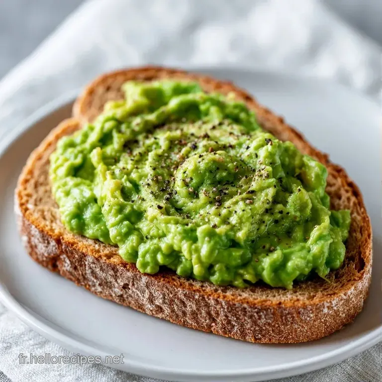 Tartine color&eacute;e pos&eacute;e sur une assiette blanche, d&eacute;cor&eacute;e de fines tranches d'avocat et d'un filet d'huile d'olive.